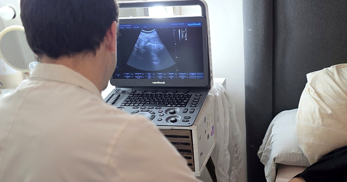 Médico radiólogo revisando una ecografía en el equipo portátil, en el domicilio del paciente